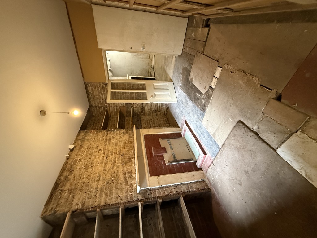 Lot: 44 - MIXED RESIDENTIAL AND COMMERCIAL BUILDING WITH POTENTIAL - View of second basement room with disused fireplace, shelving and entrance to main basement room